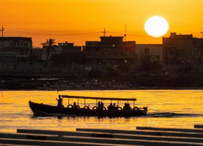TOPSHOT - A leisure boat cruises in the Shatt al-Arab waterway, formed at the confluence of the Tigris and Euphrates rivers, at sunset in Iraq's southern city of Basra during the Muslim holy month of Ramadan on April 14, 2023. (Photo by Hussein Faleh / AFP) (Photo by HUSSEIN FALEH/AFP via Getty Images)