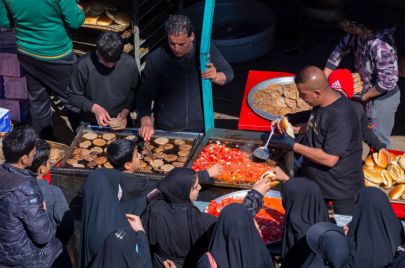 Iraqi Shiite Muslim pilgrims receive food from volunteers as they march from the centre of Baghdad toward the shrine of the 8th-century Imam Musa al-Kadhim in the Kadhimiya district, north of the capital, on February 15, 2023. - Pilgrims from various Iraqi provinces undertake a march on foot to reach the shrine in the capital to commemorate the eighth century death of Imam Musa, who is believed to have been poisoned by agents of the then ruler Harun al-Rashid. (Photo by Murtadha RIDHA / AFP) / The erroneous