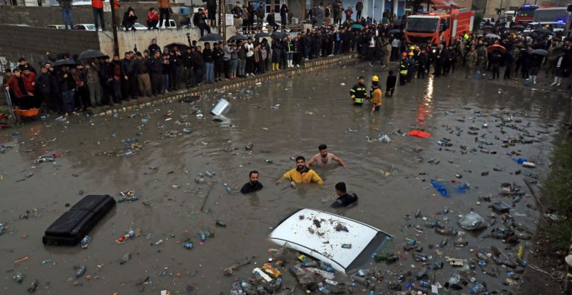 ERBIL, IRAQ - FEBRUARY 15: Firefighters and civilians try to rescue a vehicle stuck in the flooded area after heavy rains cause flash floods in Erbil, Iraq on February 15, 2024. (Photo by Ahsan Mohammed Ahmed Ahmed/Anadolu via Getty Images)