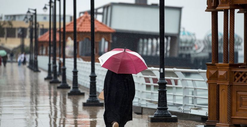 A person walks with an umbrella along a promenade by the Shatt al-Arab waterway in the southern Iraqi city of Basra following heavy rains across Iraq, on March 19, 2024. (Photo by Hussein Faleh / AFP) (Photo by HUSSEIN FALEH/AFP via Getty Images)